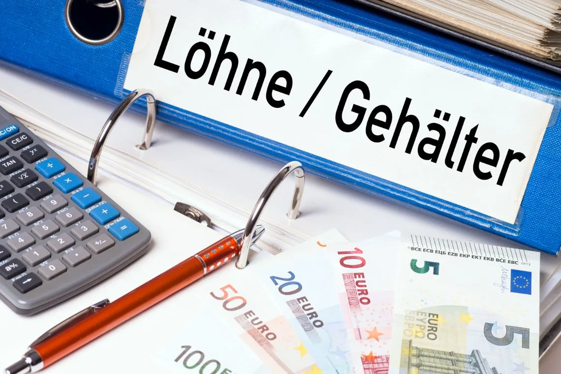Schreibtisch mit Lohnunterlagen und Taschenrechner